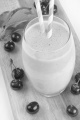 milkshake with cherries and straw on a wooden board