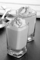 caramel dessert with whipped cream and cocoa powder in a shot glass