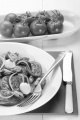 italian potato pancake with tomato, thyme, mozzarella, lilac onion and mussel on a white plate